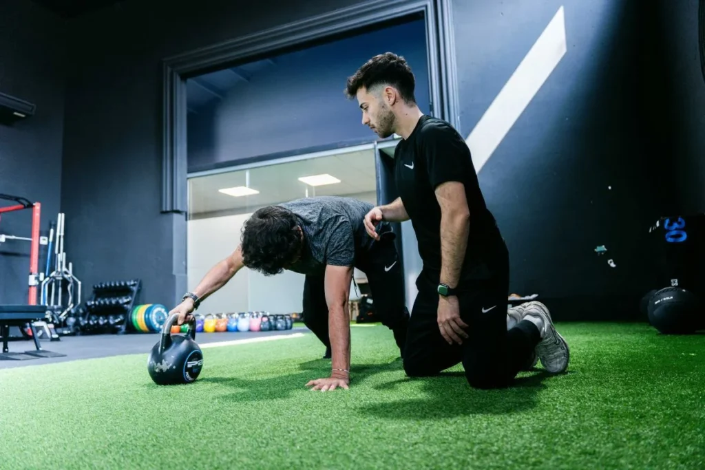 Ejercicio funcional de readaptación Paciente realizando un ejercicio funcional con kettlebell durante una readaptación deportiva en Girona